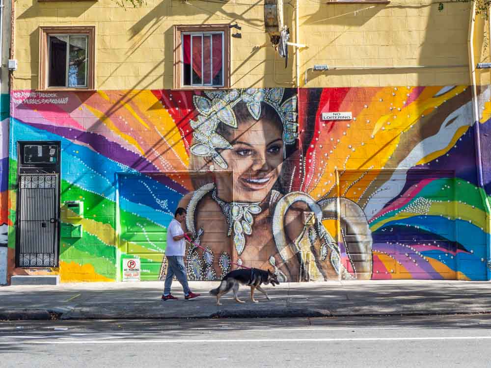 Carnavale mural in the Mission District by Crayone. A woman in costume with a rainbow background.