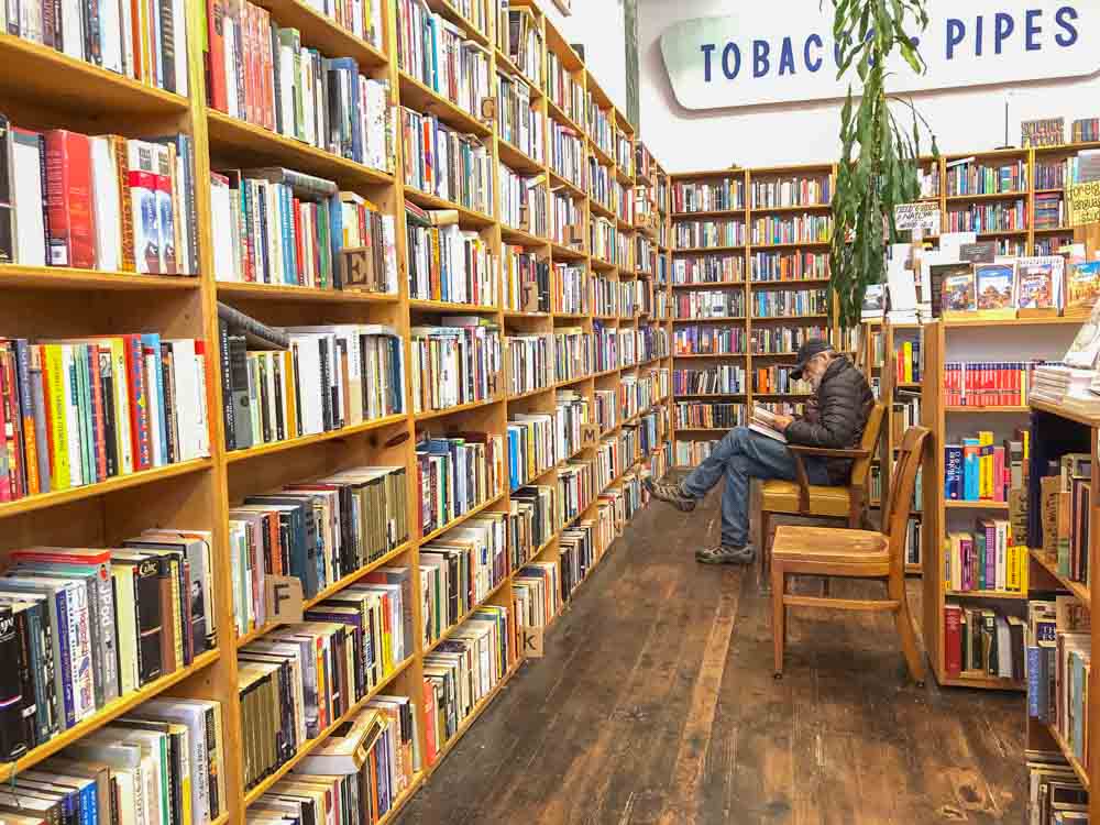 SF independent bookstores: Dog Eared Books. Man in bookshelves