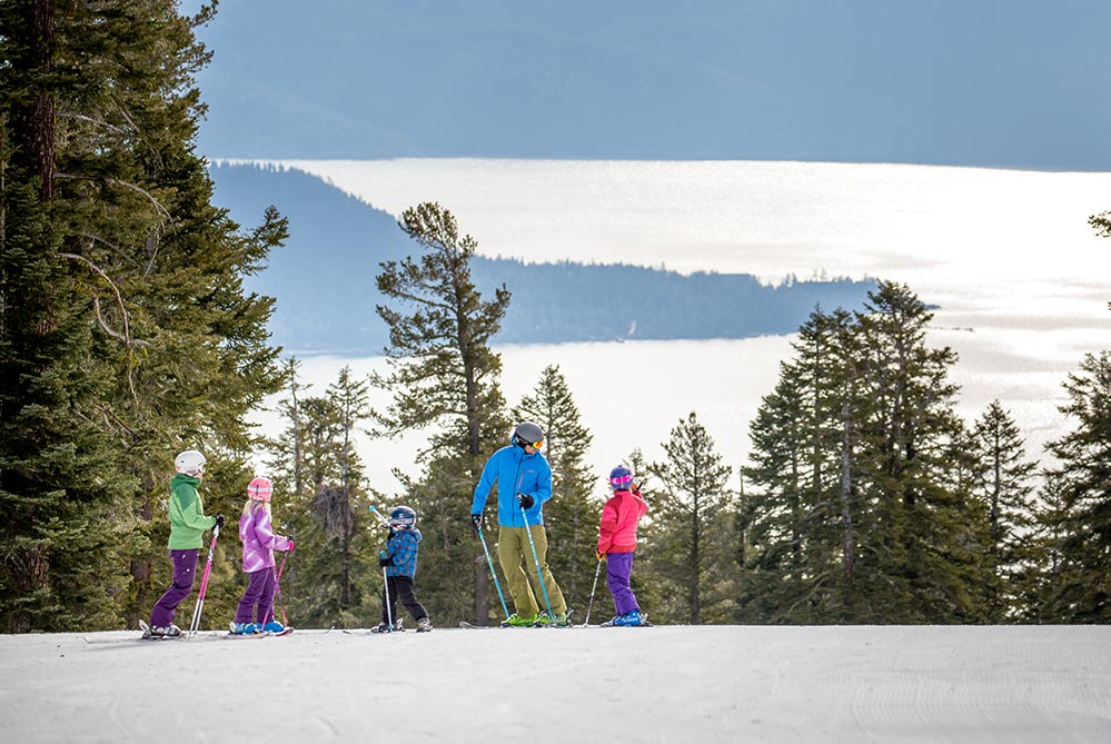 Skiers in Lake Tahoe Northstar ski resort. family on a mountain with pine trees