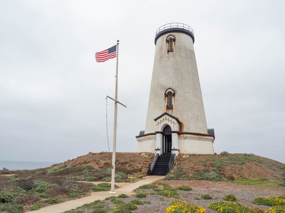 Big Sur Piedras Blancas light station. white lighthouse and american flag