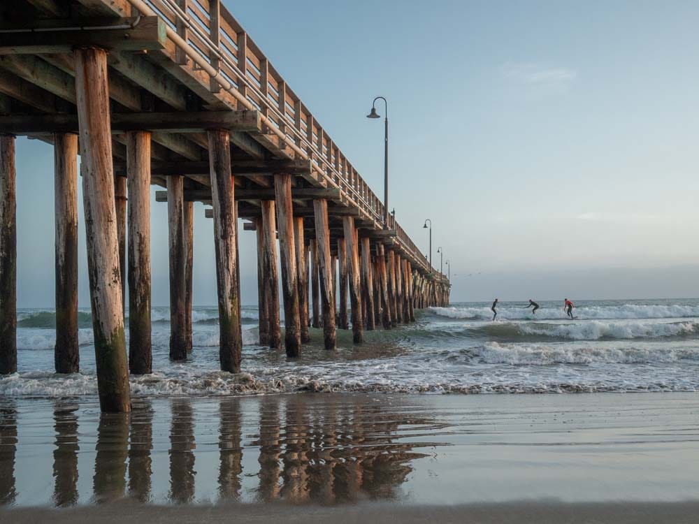 Cayucos beach and pier with surfers at sunset