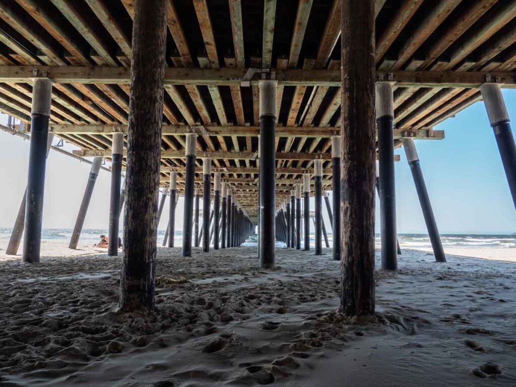 Pismo Beach pier underneath, wood piling and sand.